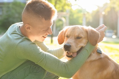 Young man with his lovely dog in park on sunny day