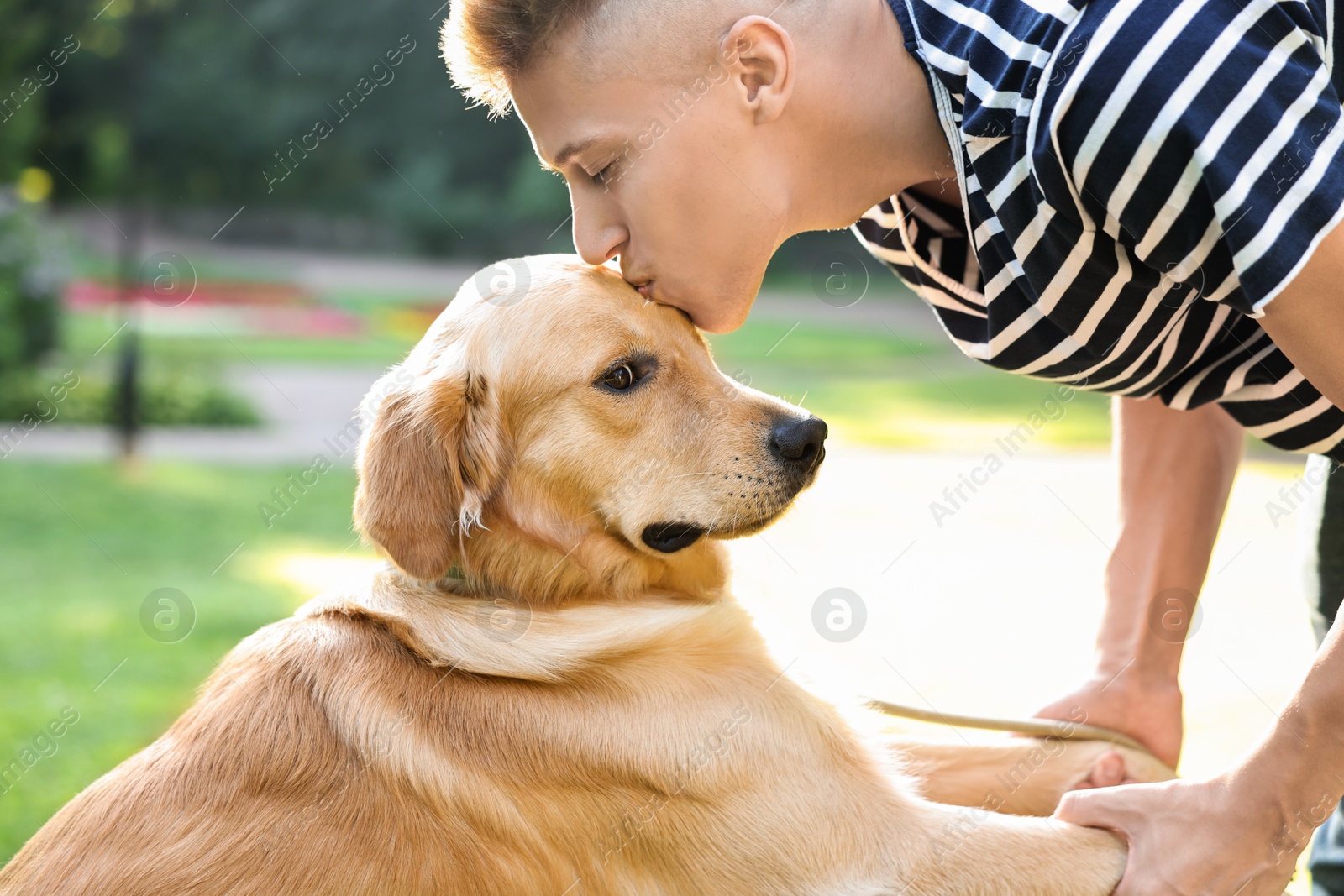 Photo of Young man kissing his lovely dog in park