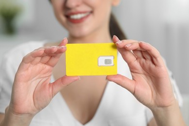 Photo of Woman holding SIM card at home, closeup