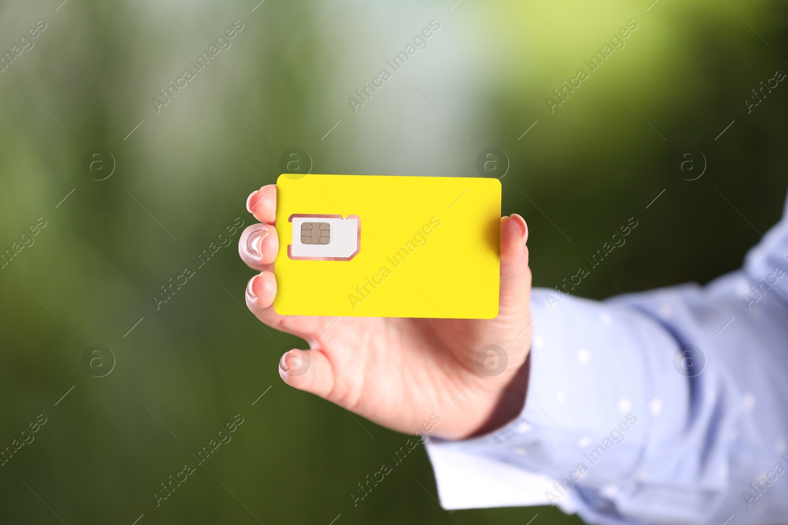 Photo of Woman holding SIM card on blurred background, closeup