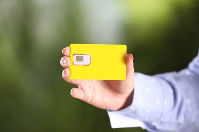 Photo of Woman holding SIM card on blurred background, closeup