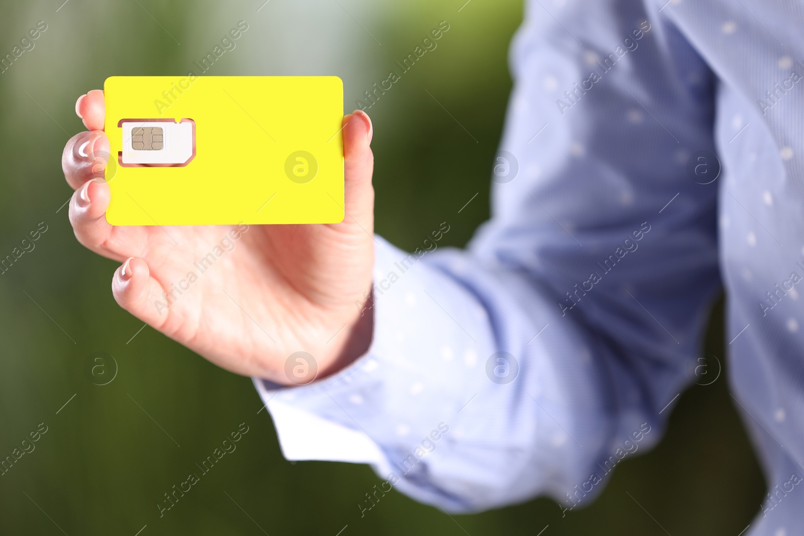 Photo of Woman holding SIM card on blurred background, closeup