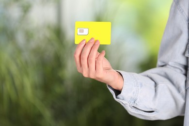 Photo of Woman holding SIM card on blurred background, closeup