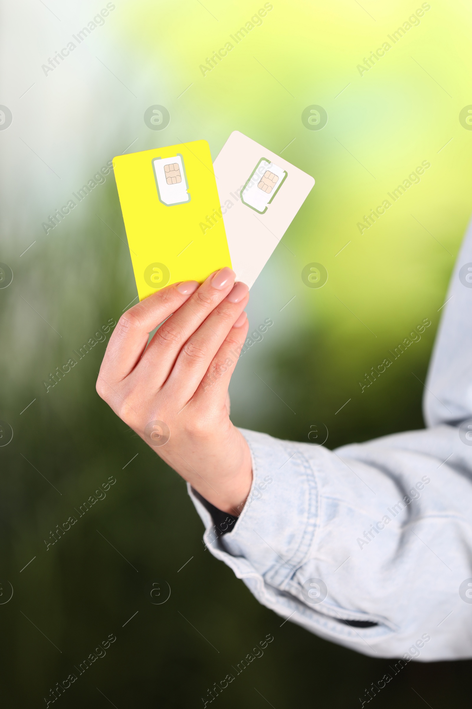 Photo of Woman holding SIM cards on blurred background, closeup