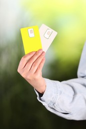 Photo of Woman holding SIM cards on blurred background, closeup