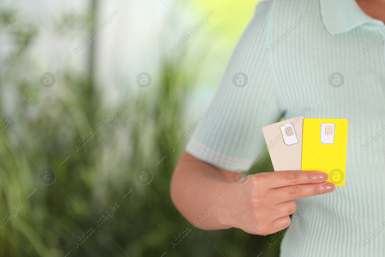 Photo of Woman holding SIM cards on blurred background, closeup. Space for text