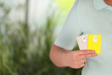 Photo of Woman holding SIM cards on blurred background, closeup. Space for text