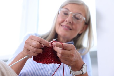 Smiling woman knitting at home, selective focus