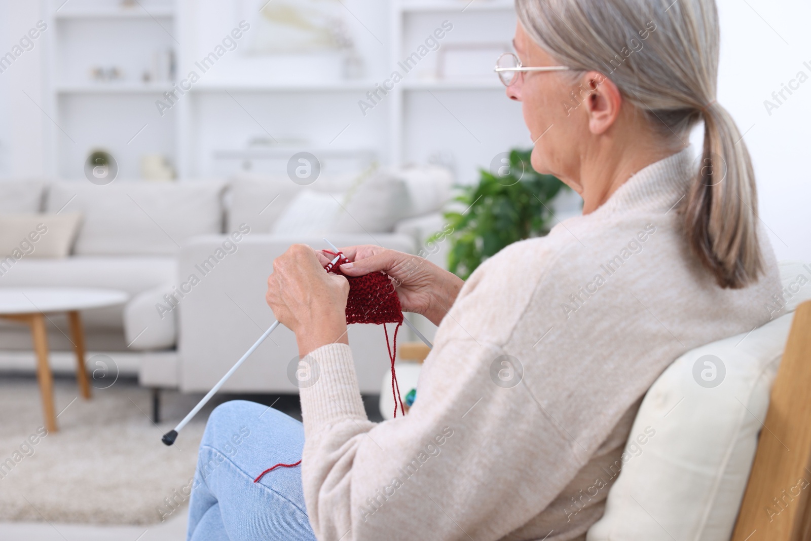 Photo of Senior woman in glasses knitting at home. Handicraft hobby