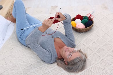 Beautiful senior woman knitting on bed at home, above view