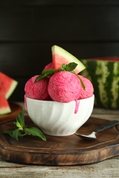 Scoops of tasty watermelon sorbet in bowl, fresh fruit, mint and spoon on wooden table