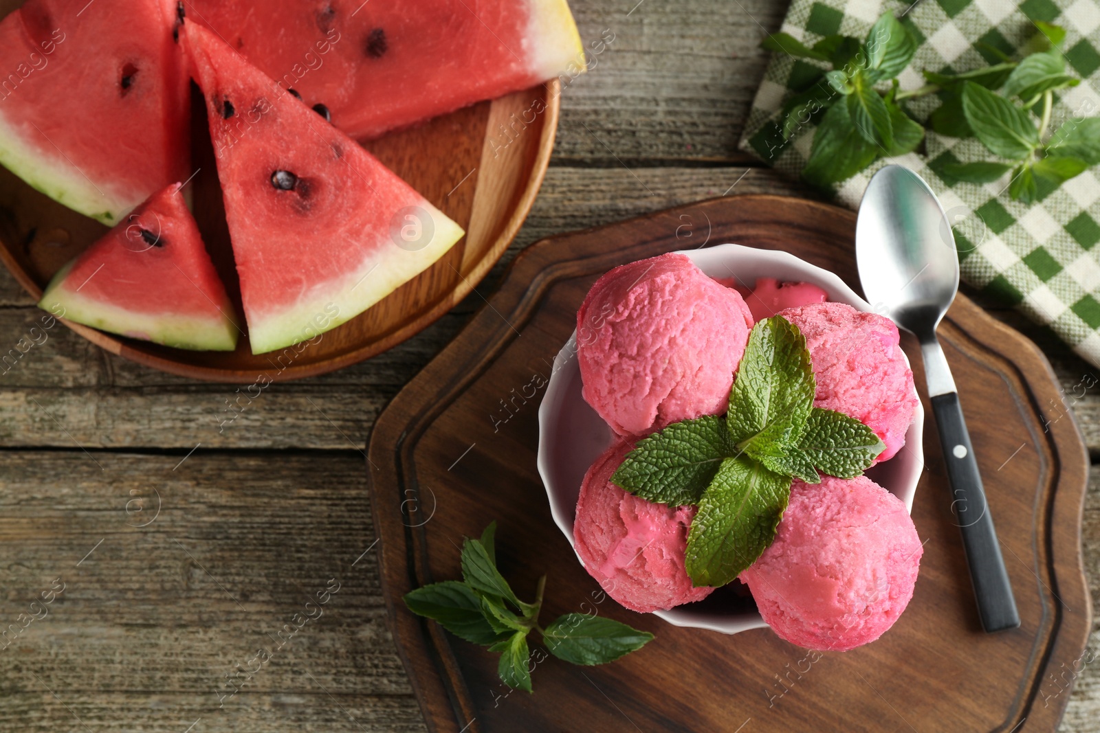 Photo of Scoops of tasty watermelon sorbet in bowl, fresh fruit, mint and spoon on wooden table, top view