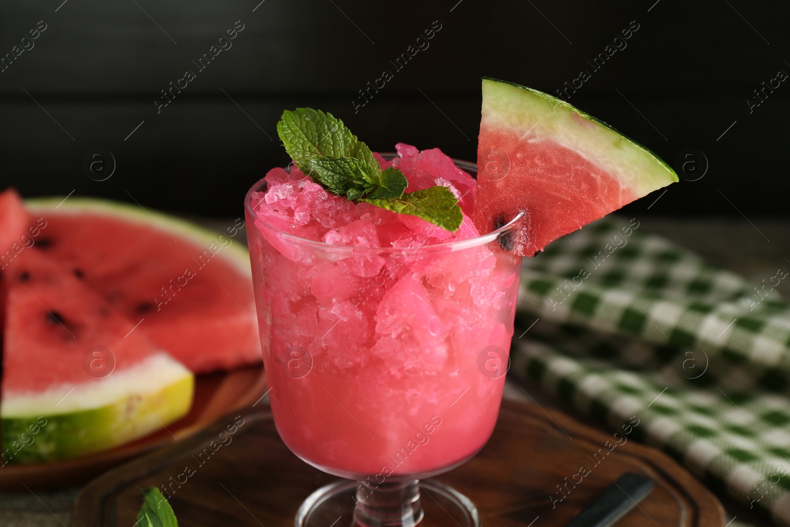 Photo of Tasty watermelon sorbet in glass dessert bowl, fresh fruit and mint on table, closeup