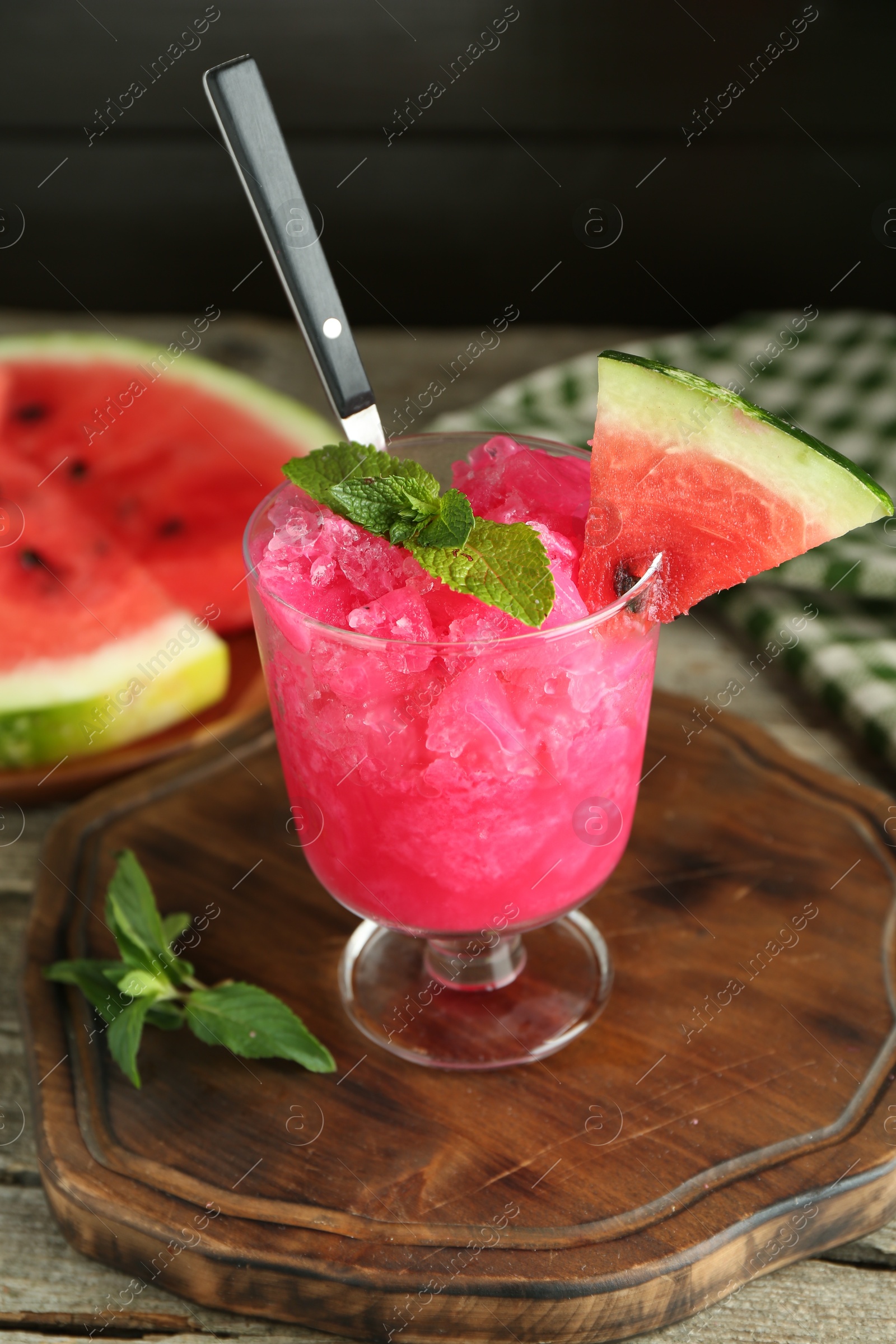 Photo of Tasty watermelon sorbet in glass dessert bowl, fresh fruit and mint on wooden table