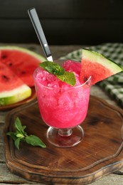 Photo of Tasty watermelon sorbet in glass dessert bowl, fresh fruit and mint on wooden table