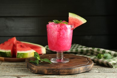 Tasty watermelon sorbet in glass dessert bowl, fresh fruit and mint on wooden table