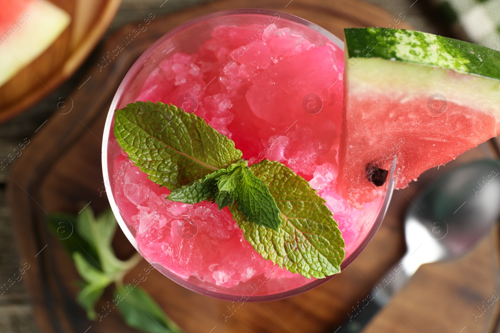 Photo of Tasty watermelon sorbet in glass dessert bowl, fresh fruit, mint and spoon on table, top view