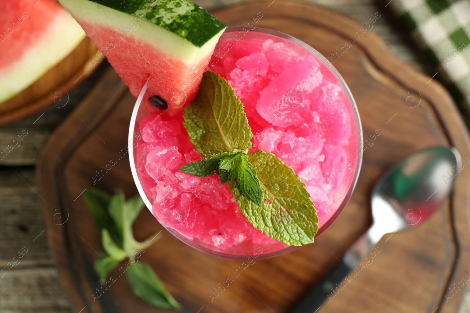 Photo of Tasty watermelon sorbet in glass dessert bowl, fresh fruit, mint and spoon on table, top view