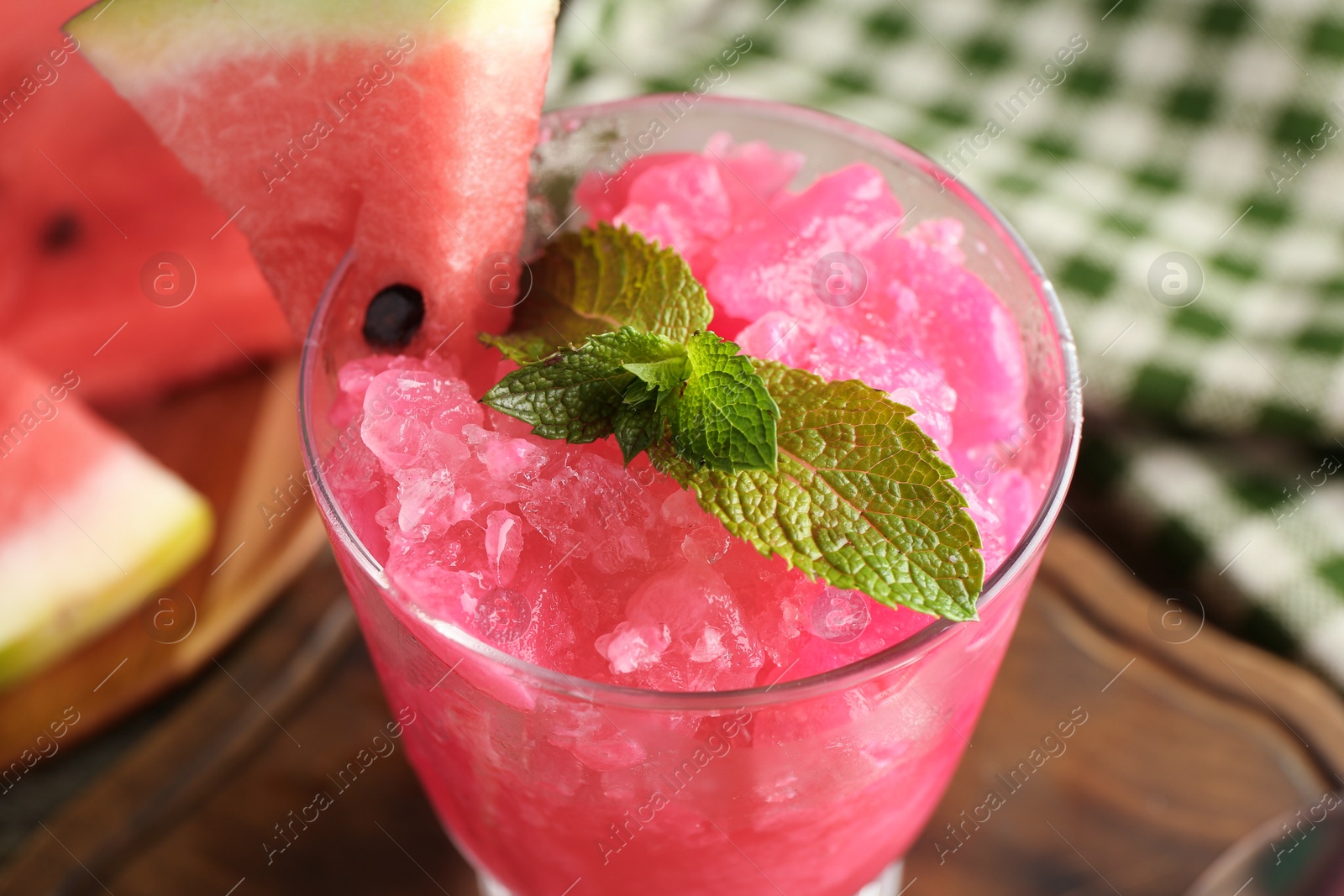 Photo of Tasty watermelon sorbet in glass dessert bowl, fresh fruit and mint on table, closeup