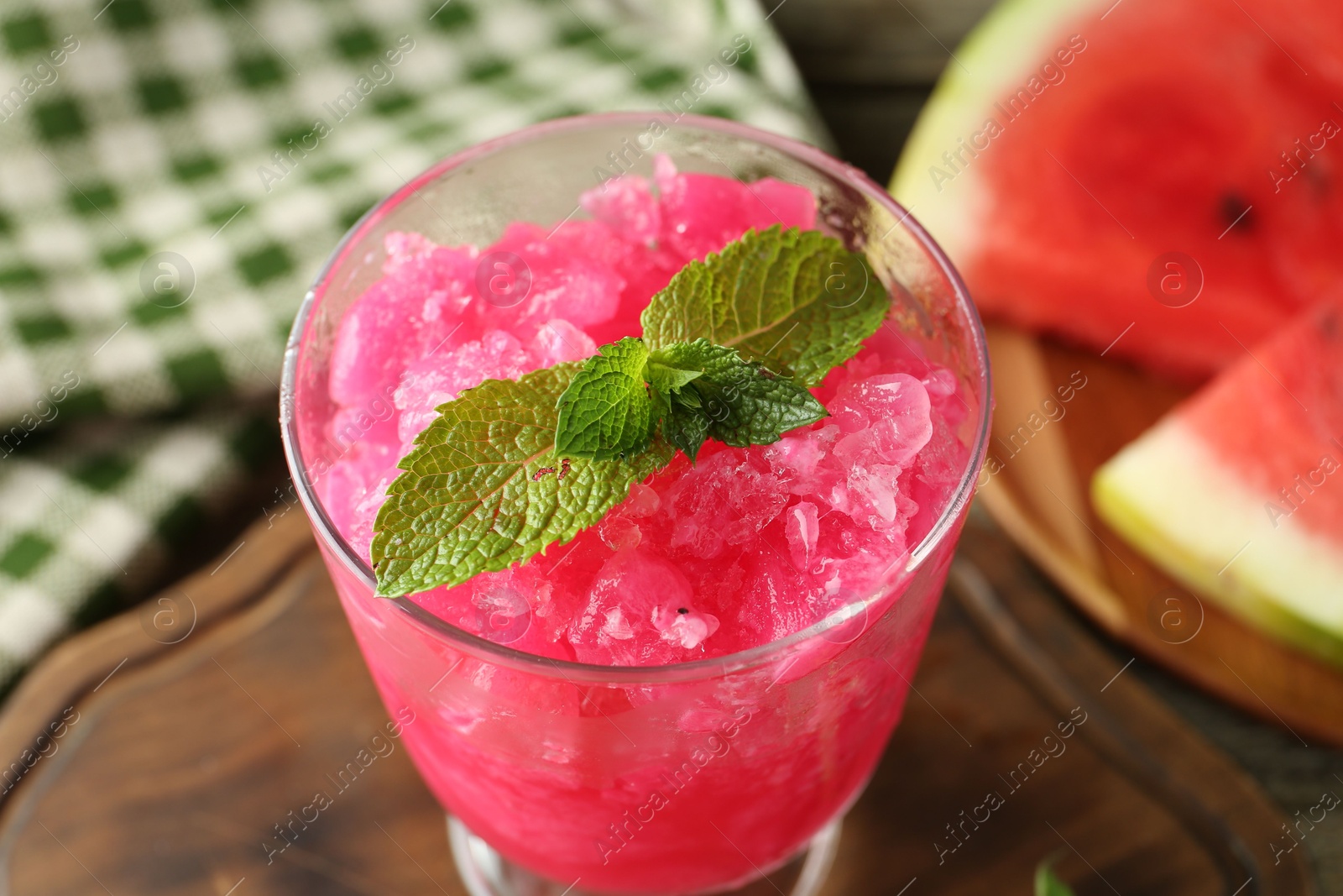 Photo of Tasty watermelon sorbet in glass dessert bowl, fresh fruit and mint on table, closeup