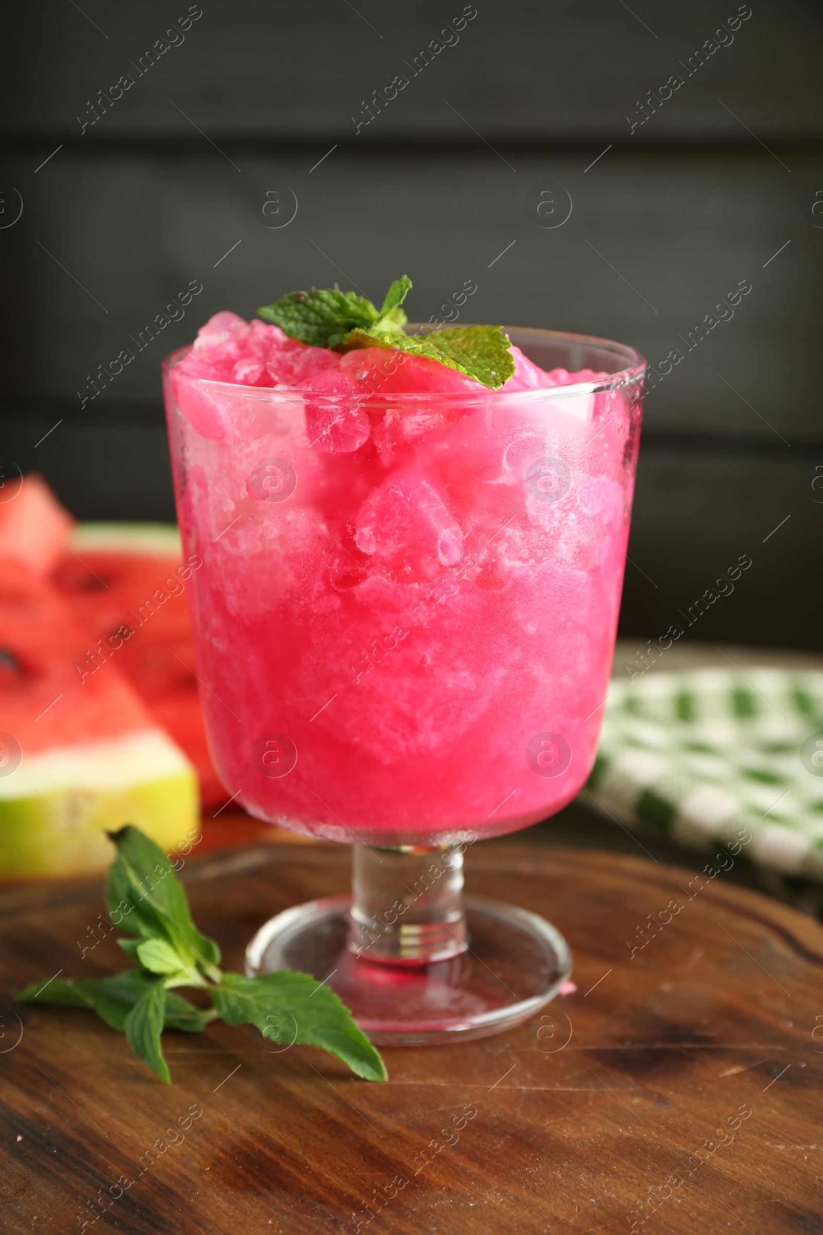 Photo of Tasty watermelon sorbet in glass dessert bowl and mint on table, closeup