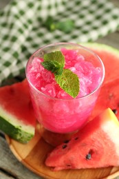 Tasty watermelon sorbet in glass dessert bowl, fresh fruit and mint on table, closeup