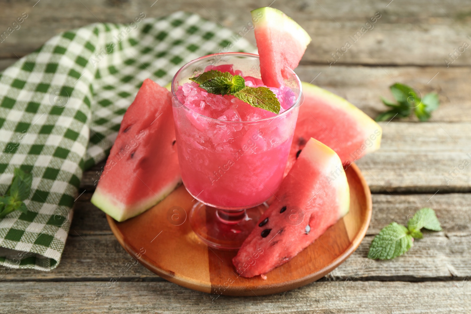 Photo of Tasty watermelon sorbet in glass dessert bowl, fresh fruit and mint on wooden table