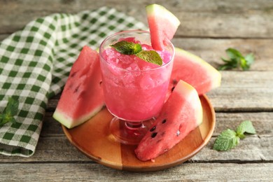 Photo of Tasty watermelon sorbet in glass dessert bowl, fresh fruit and mint on wooden table