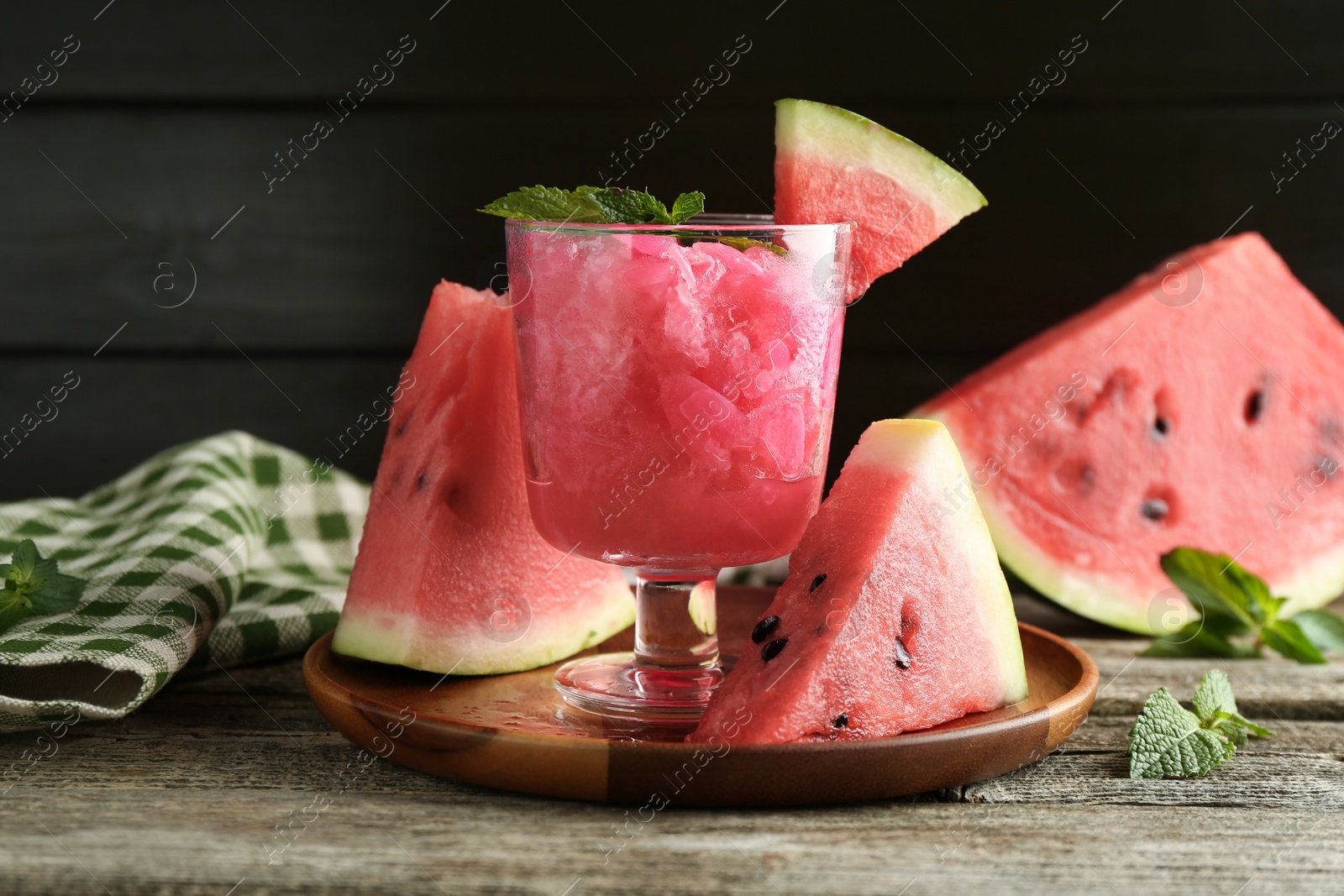 Photo of Tasty watermelon sorbet in glass dessert bowl, fresh fruit and mint on wooden table