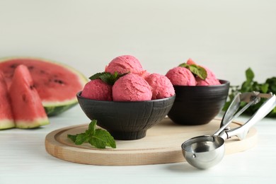 Photo of Scoops of tasty watermelon sorbet in bowls, fresh fruit and mint on white wooden table