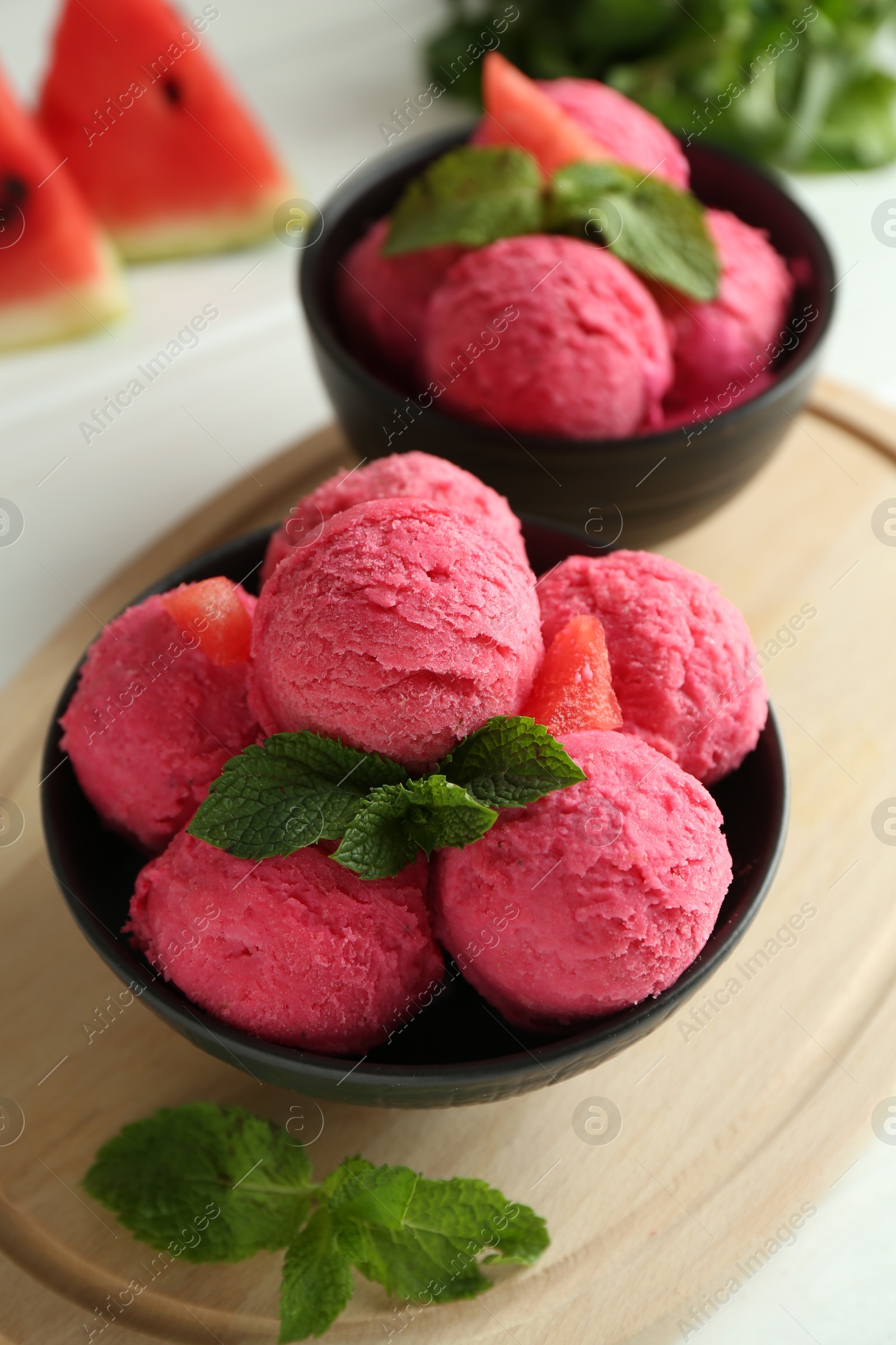 Photo of Scoops of tasty watermelon sorbet in bowls and mint on white table, closeup