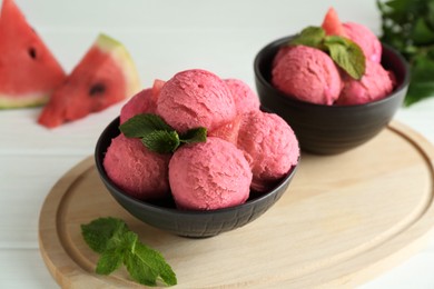 Photo of Scoops of tasty watermelon sorbet in bowls and mint on white wooden table