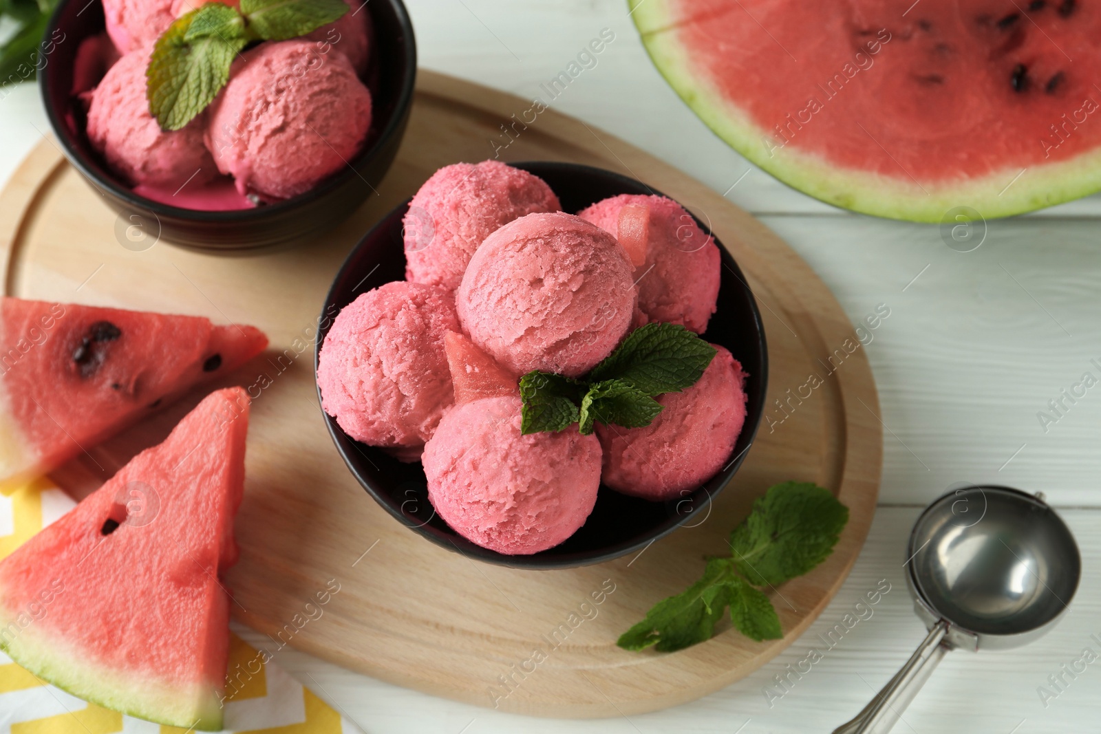 Photo of Scoops of tasty watermelon sorbet in bowls, fresh fruit and mint on white wooden table, above view