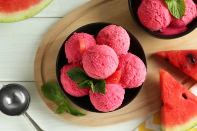 Photo of Scoops of tasty watermelon sorbet in bowls, fresh fruit and mint on white wooden table, top view