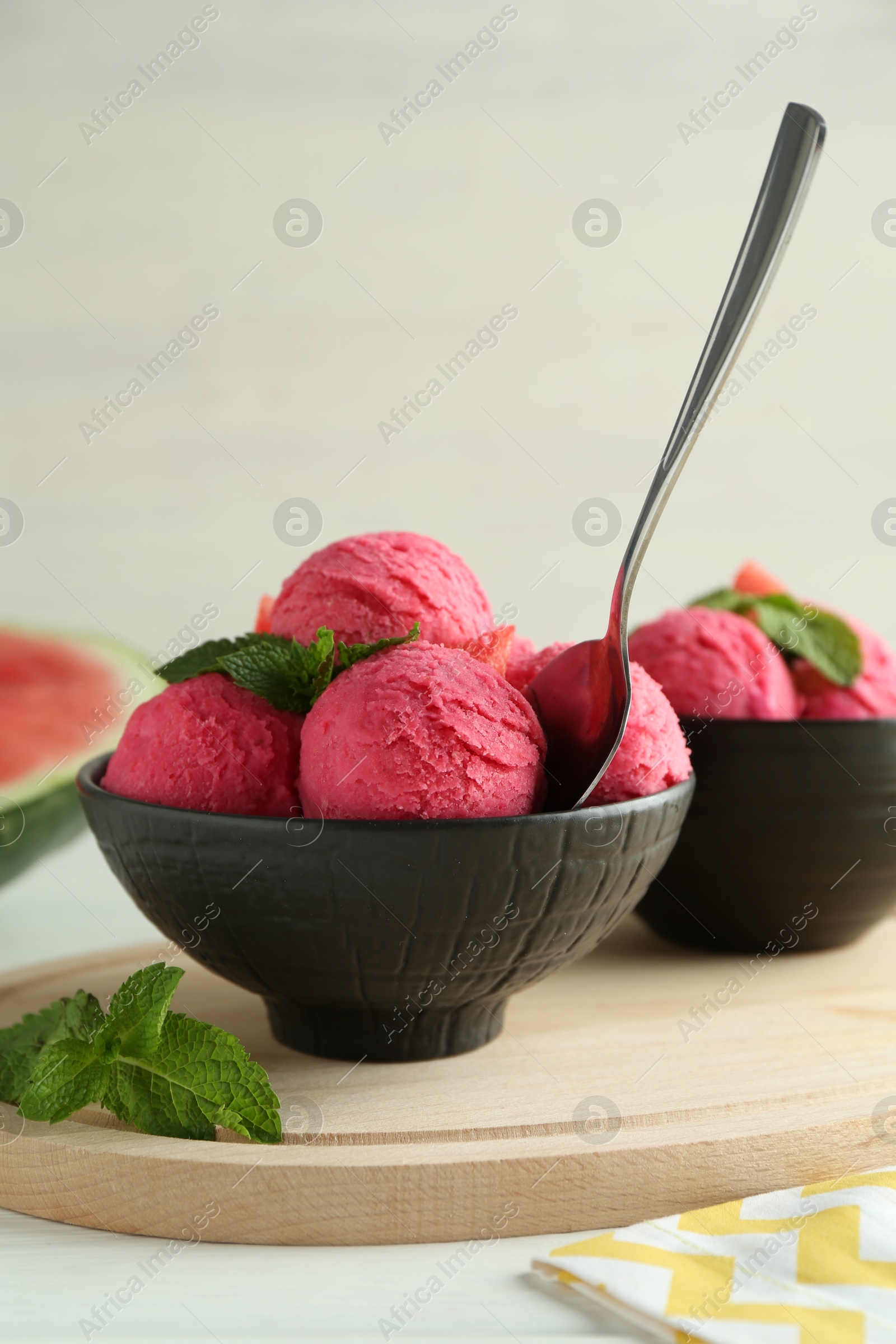 Photo of Scoops of tasty watermelon sorbet in bowls, mint and spoon on white table