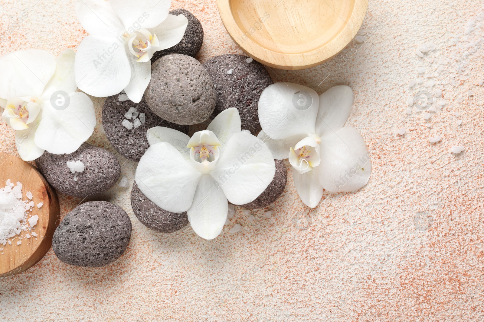 Photo of Spa stones, sea salt and beautiful orchid flowers on beige textured background, flat lay