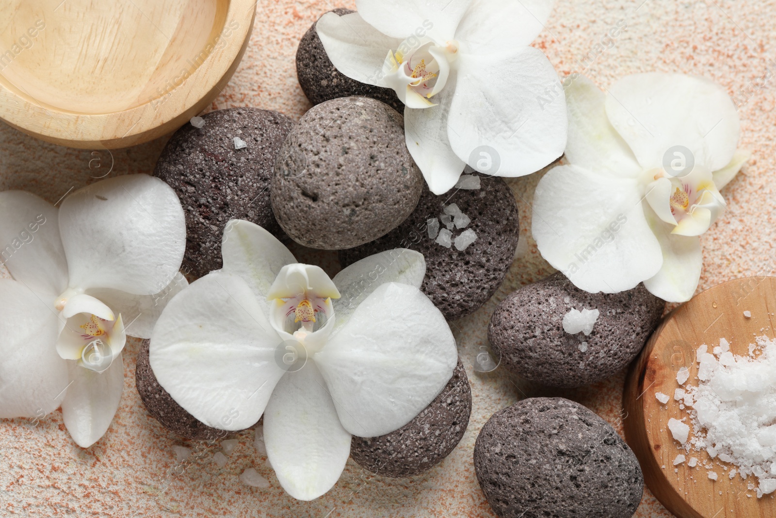 Photo of Spa stones, sea salt and beautiful orchid flowers on beige textured background, flat lay