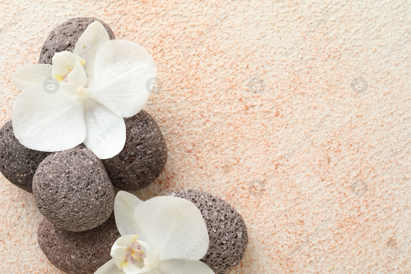 Photo of Spa stones and beautiful orchid flowers on beige textured background, flat lay. Space for text