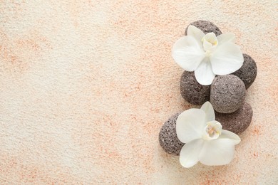 Spa stones and beautiful orchid flowers on beige textured background, flat lay. Space for text