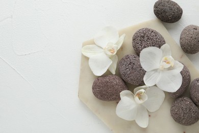 Spa stones and beautiful orchid flowers on white textured background, flat lay. Space for text