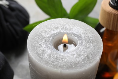 Photo of Burning candle on grey table, closeup view