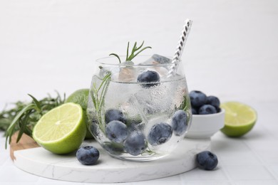 Refreshing water with blueberries and rosemary on white tiled table