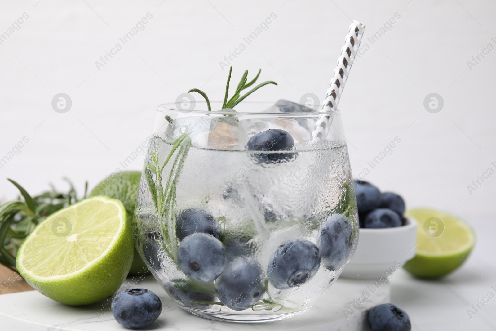 Photo of Refreshing water with blueberries and rosemary on white table, closeup