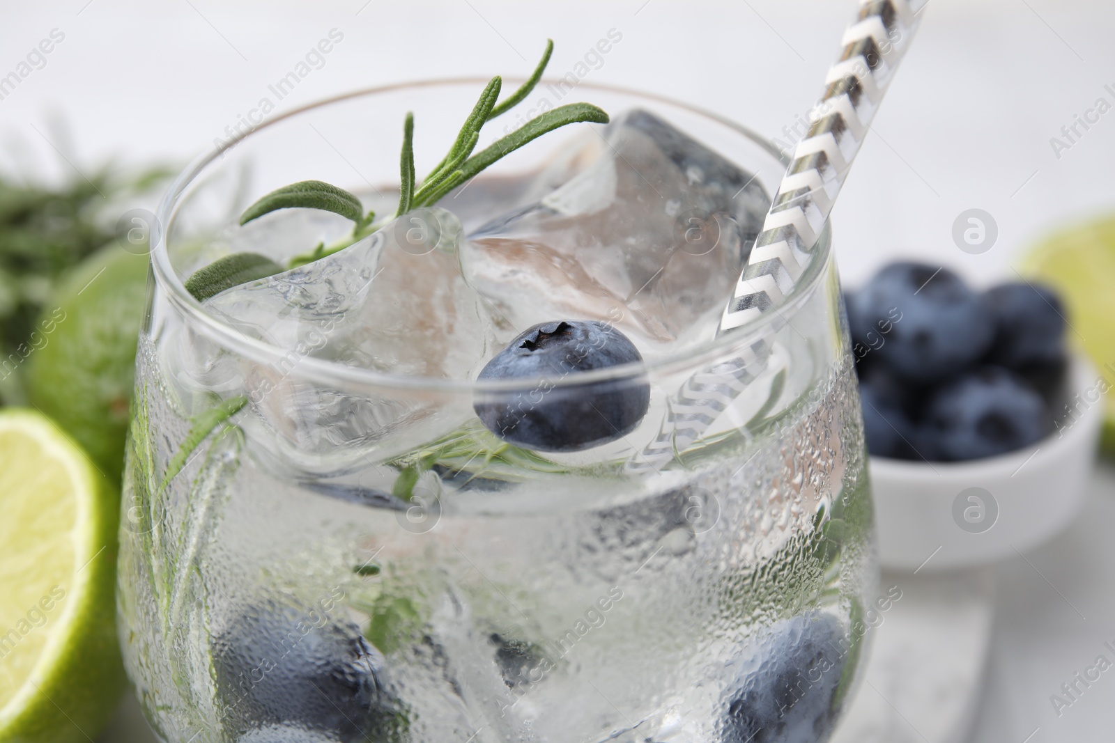 Photo of Refreshing water with blueberries and rosemary in glass on white table, closeup