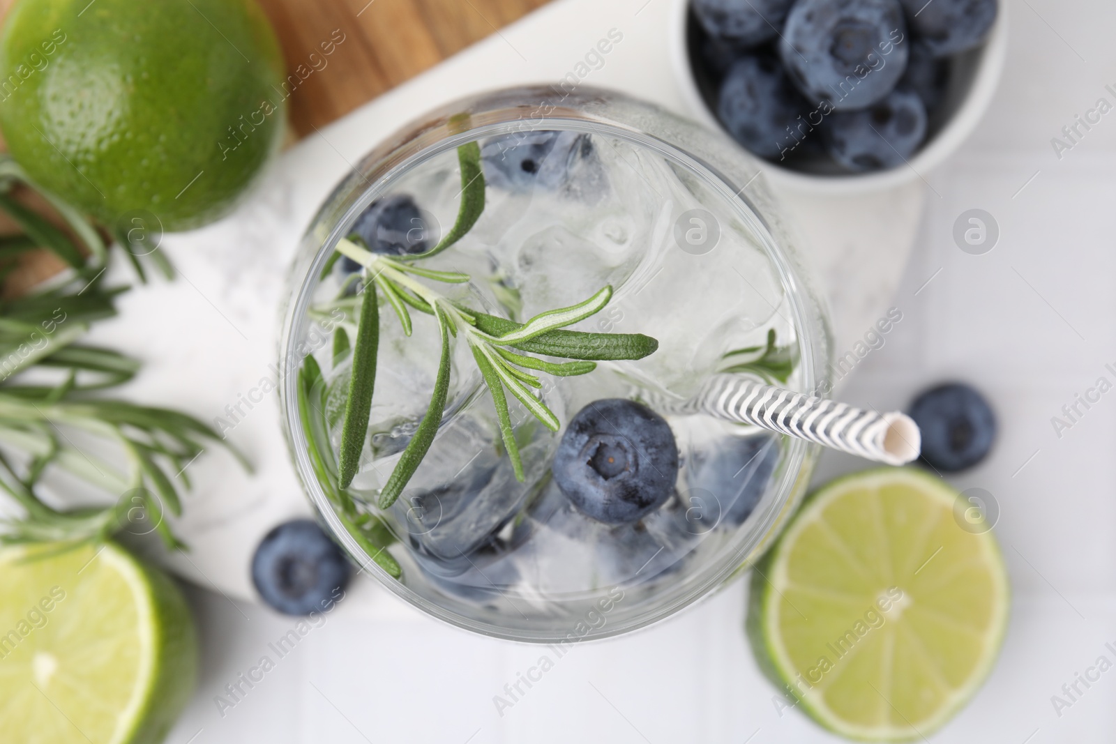 Photo of Refreshing water with blueberries and rosemary in glass on white table, flat lay