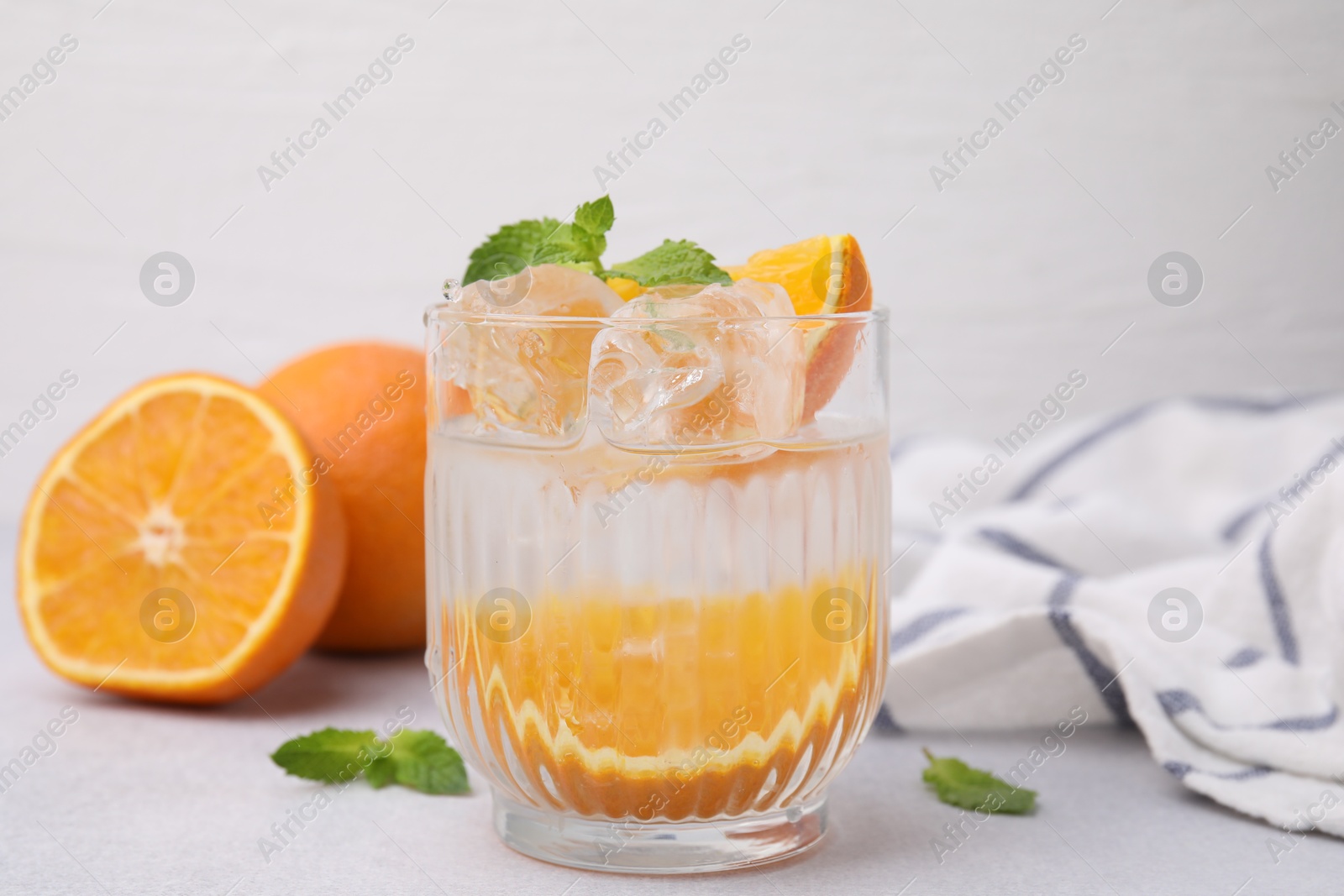 Photo of Refreshing water with orange and mint in glass on light table, closeup