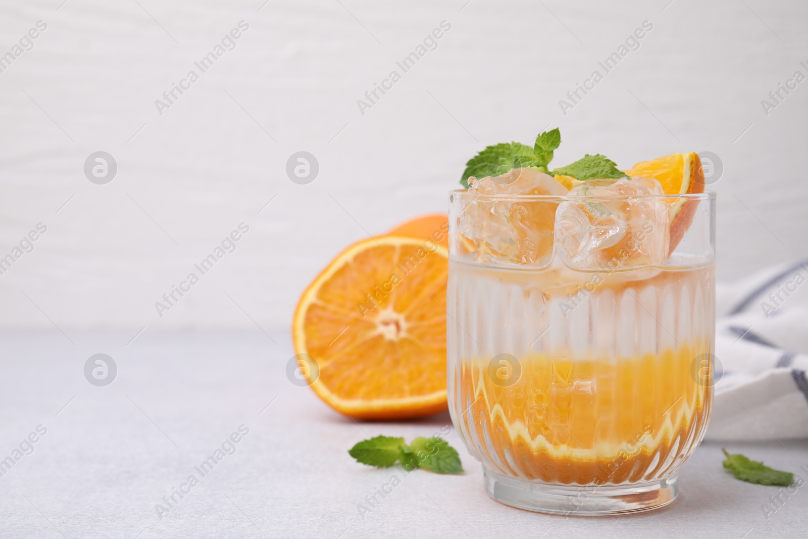 Photo of Refreshing water with orange and mint in glass on light table, space for text