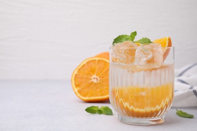 Refreshing water with orange and mint in glass on light table, space for text