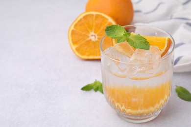 Photo of Refreshing water with orange and mint in glass on light table, closeup. Space for text