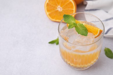 Refreshing water with orange and mint in glass on light table, closeup. Space for text